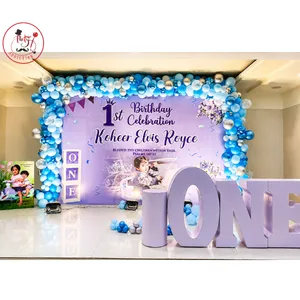 First birthday celebration decoration with personalized backdrop, balloon frame, large ONE lettering and decorative cylinder stands